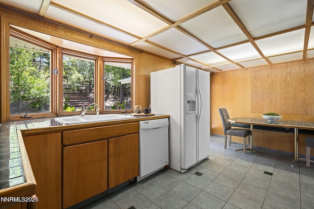 2770 Solari Dr, Reno, NV 89509 - kitchen with white appliances, a sink, light tile patterned floors, brown cabinets, and wooden walls