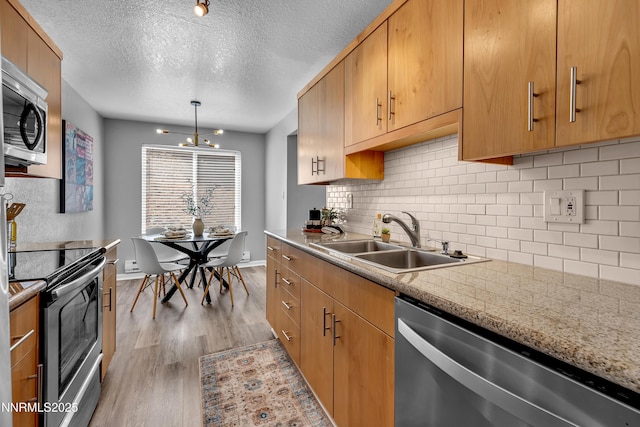 3951 Clear Acre Ln Unit 293, Reno, NV 89512 - kitchen featuring stainless steel appliances, a sink, light wood-type flooring, decorative backsplash, and a textured ceiling