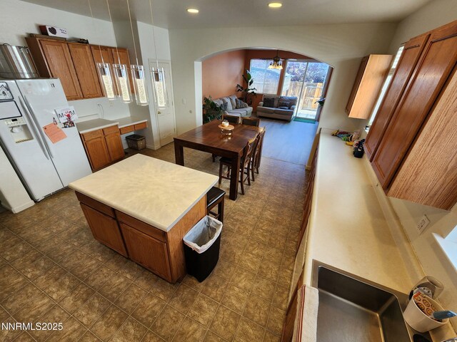 1224 Mountain Rose Dr, Fernley, NV 89408 - kitchen with white refrigerator with ice dispenser, arched walkways, brown cabinetry, recessed lighting, and light countertops