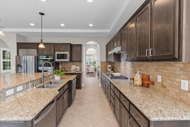 2675 Weymoor Ct, Reno, NV 89521 - kitchen with arched walkways, stainless steel appliances, a sink, dark brown cabinets, and decorative backsplash