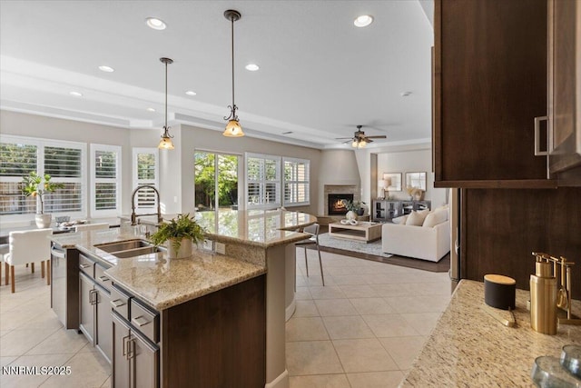 2675 Weymoor Ct, Reno, NV 89521 - kitchen with a sink, ceiling fan, dark brown cabinets, a warm lit fireplace, and light tile patterned floors