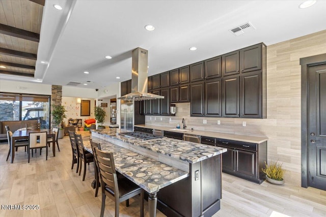 2675 Weymoor Ct, Reno, NV 89521 - kitchen with island range hood, appliances with stainless steel finishes, a kitchen breakfast bar, a sink, and dark brown cabinets
