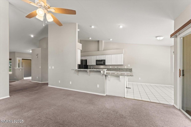 4515 Vista Mountain Dr, Sparks, NV 89436 - kitchen featuring black appliances, light colored carpet, a breakfast bar, vaulted ceiling, and baseboards