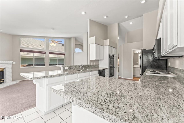 4515 Vista Mountain Dr, Sparks, NV 89436 - kitchen featuring a peninsula, a ceiling fan, a fireplace, a sink, and black appliances