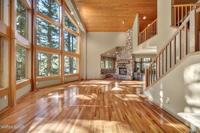 1445 Austrian Pine Rd, Reno, NV 89511 - unfurnished living room with high vaulted ceiling, wood-type flooring, stairs, a stone fireplace, and baseboards