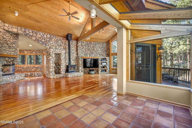 1445 Austrian Pine Rd, Reno, NV 89511 - unfurnished living room with wooden ceiling with exposed beams, a stone fireplace, ceiling fan, a wood stove, and baseboards