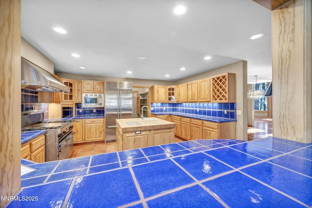 1445 Austrian Pine Rd, Reno, NV 89511 - kitchen with built in appliances, backsplash, a kitchen island with sink, wall chimney range hood, and glass insert cabinets
