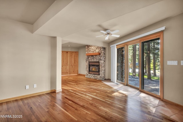 1445 Austrian Pine Rd, Reno, NV 89511 - unfurnished living room featuring baseboards, wood finished floors, a stone fireplace, and ceiling fan