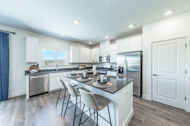 7609 Apex Pl # 113, Reno, NV 89506 - kitchen with appliances with stainless steel finishes, a sink, dark countertops, a breakfast bar area, and white cabinets