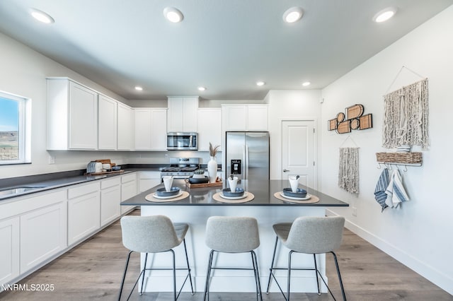 7609 Apex Pl # 113, Reno, NV 89506 - kitchen with stainless steel appliances, dark countertops, a kitchen bar, white cabinetry, and recessed lighting