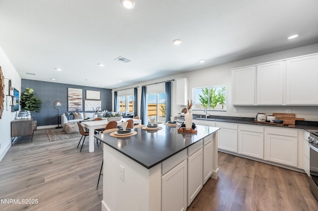 7609 Apex Pl # 113, Reno, NV 89506 - kitchen with a sink, dark countertops, light wood finished floors, white cabinets, and recessed lighting