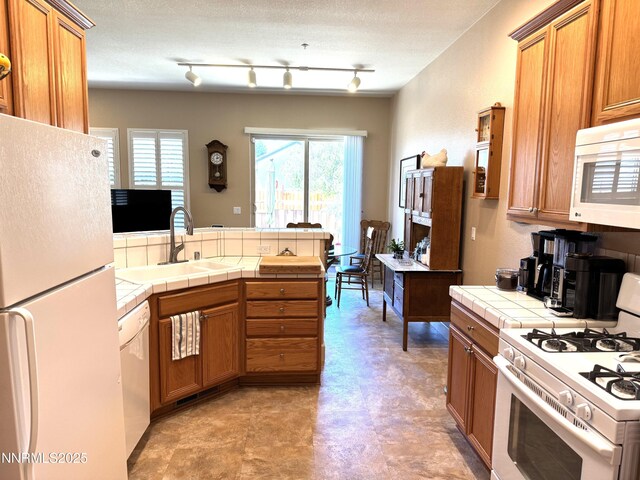 6680 Aston Cir, Sparks, NV 89436 - kitchen featuring white appliances, tile counters, light flooring, brown cabinetry, and a peninsula
