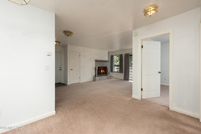 769 Tina Ct # H, Stateline, NV 89449 - unfurnished living room featuring light carpet, a tiled fireplace, and baseboards