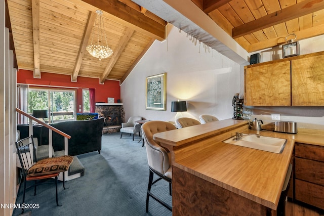 383 Tramway Dr Unit B, Stateline, NV 89449 - kitchen with wooden ceiling with exposed beams, a sink, carpet flooring, a chandelier, and a stone fireplace