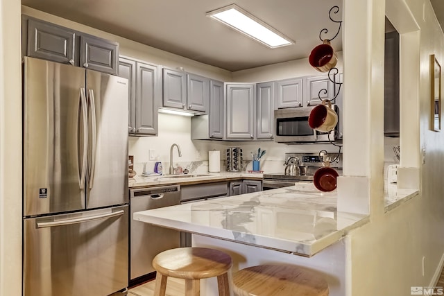758 Milky Way Ct Unit B, Stateline, NV 89449 - kitchen featuring appliances with stainless steel finishes, a peninsula, gray cabinetry, a sink, and a kitchen bar