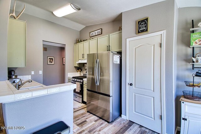 1563 Maria Ct, Fernley, NV 89408 - kitchen featuring stainless steel appliances, tile countertops, under cabinet range hood, lofted ceiling, and light wood finished floors