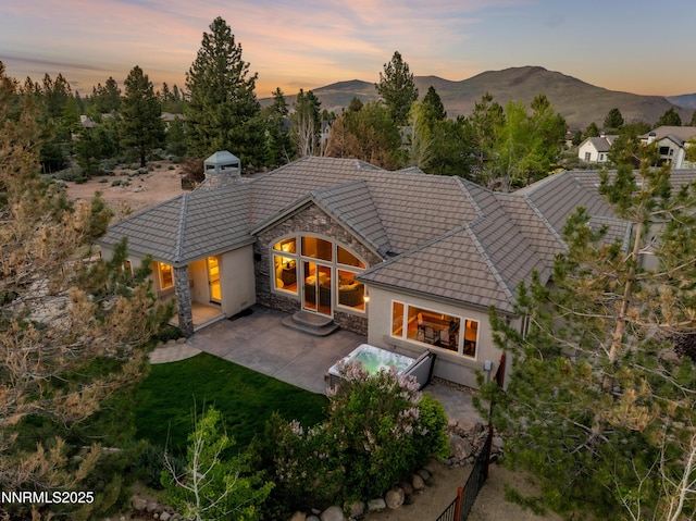 193 N Argyle Ct, Reno, NV 89511 - rear view of property with stone siding, a tile roof, a patio area, a chimney, and a mountain view