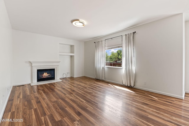 3095 Fairwood Dr, Reno, NV 89502 - unfurnished living room featuring a glass covered fireplace, built in features, wood finished floors, and baseboards
