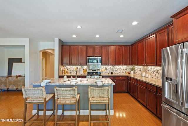 11285 Messina Way, Reno, NV 89521 - kitchen with appliances with stainless steel finishes, light wood-style floors, a sink, arched walkways, and recessed lighting
