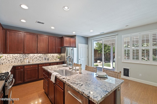 11285 Messina Way, Reno, NV 89521 - kitchen with stainless steel appliances, light wood-type flooring, light stone countertops, a sink, and backsplash