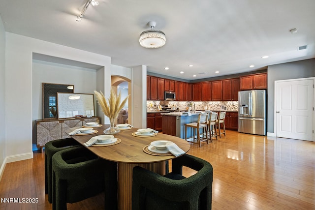 11285 Messina Way, Reno, NV 89521 - dining room with arched walkways, baseboards, light wood-style flooring, recessed lighting, and rail lighting