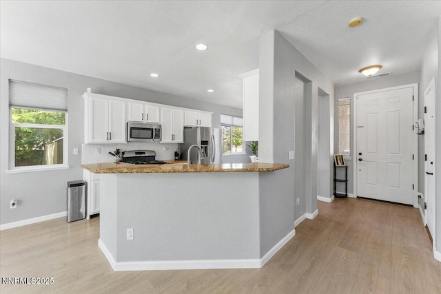 2349 Dodge Dr, Sparks, NV 89436 - kitchen featuring stainless steel appliances, light wood-style flooring, light stone counters, white cabinets, and baseboards