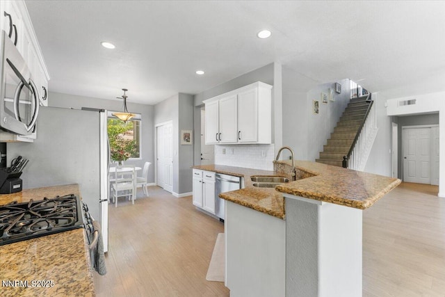 2349 Dodge Dr, Sparks, NV 89436 - kitchen with a sink, stainless steel appliances, light wood finished floors, light stone counters, and white cabinets