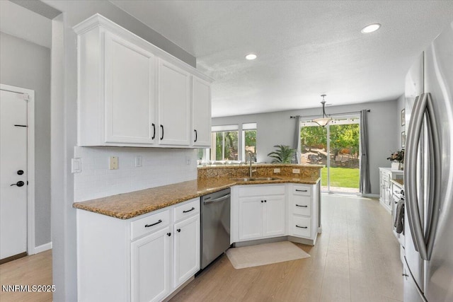 2349 Dodge Dr, Sparks, NV 89436 - kitchen with a sink, appliances with stainless steel finishes, a peninsula, white cabinets, and light wood finished floors