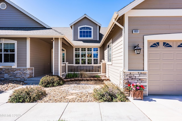 1601 Jones St, Minden, NV 89423 - view of exterior entry with a porch, stone siding, a garage, and roof with shingles