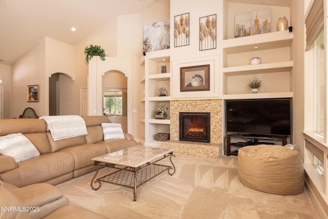1601 Jones St, Minden, NV 89423 - carpeted living area featuring arched walkways, built in shelves, high vaulted ceiling, a tile fireplace, and baseboards