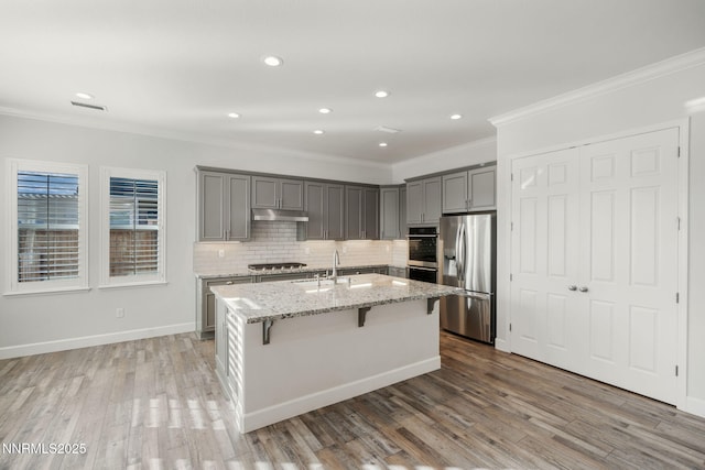 11621 Desert Shadow Dr, Sparks, NV 89441 - kitchen with stainless steel appliances, gray cabinetry, ornamental molding, under cabinet range hood, and a center island with sink