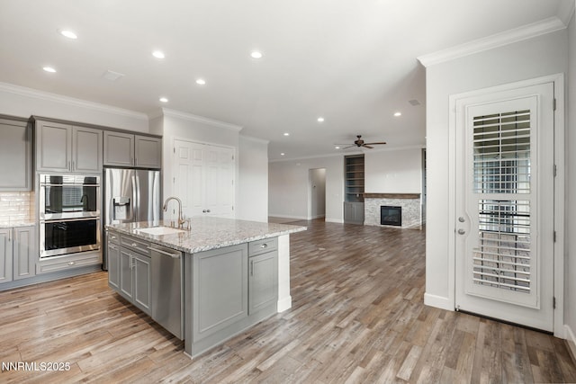 11621 Desert Shadow Dr, Sparks, NV 89441 - kitchen featuring gray cabinetry, stainless steel appliances, a sink, crown molding, and a fireplace