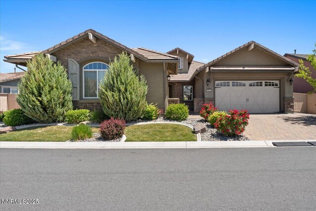 9822 Dyevera Ln, Reno, NV 89521 - view of front facade with a tiled roof, a garage, decorative driveway, stucco siding, and stone siding