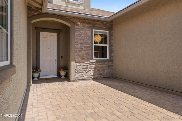 9822 Dyevera Ln, Reno, NV 89521 - doorway to property with stone siding, stucco siding, and a patio area