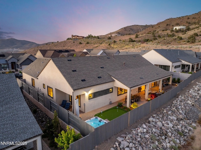 3060 Feathertop Dr, Reno, NV 89521 - back of property at dusk featuring a fenced backyard, a mountain view, a patio area, and roof with shingles