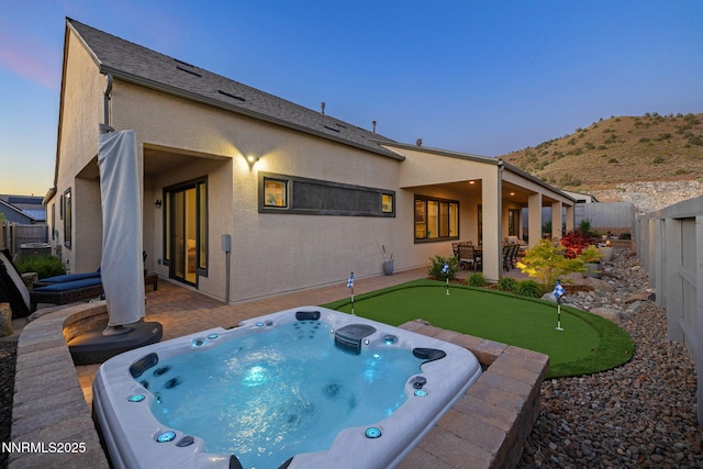 3060 Feathertop Dr, Reno, NV 89521 - rear view of property featuring an area to practice putting, a hot tub, a patio, and stucco siding