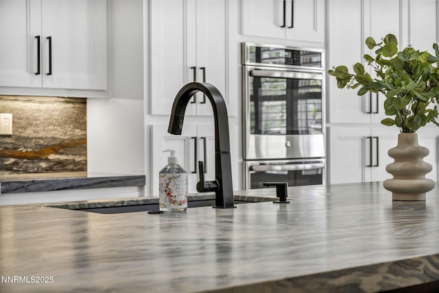 2965 Roundrock Ct, Reno, NV 89511 - kitchen view of stainless steel double oven, white cabinets, backsplash, and a sink