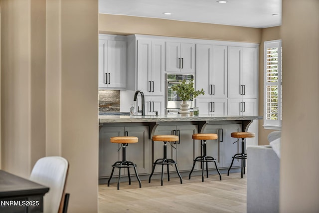 2965 Roundrock Ct, Reno, NV 89511 - kitchen with double oven, a sink, a kitchen breakfast bar, light wood-style flooring, and recessed lighting