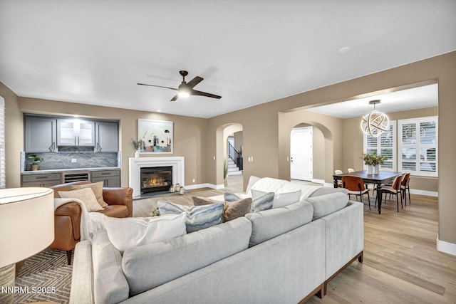 2965 Roundrock Ct, Reno, NV 89511 - living room with arched walkways, baseboards, a glass covered fireplace, and light wood-style floors