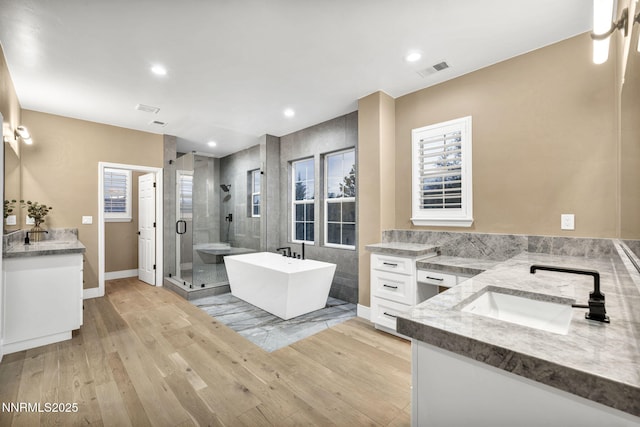 2965 Roundrock Ct, Reno, NV 89511 - full bathroom with two vanities, a shower stall, a freestanding bath, wood finished floors, and healthy amount of natural light