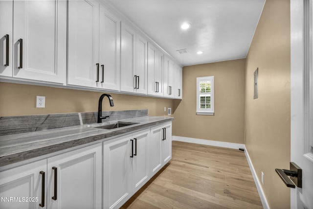 2965 Roundrock Ct, Reno, NV 89511 - kitchen with a sink, baseboards, white cabinets, dark stone countertops, and light wood-type flooring