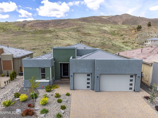 9129 Wild Skies Way, Reno, NV 89523 - contemporary home featuring an attached garage, a mountain view, decorative driveway, and stucco siding