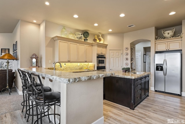 5330 Ventana Pkwy, Reno, NV 89511 - kitchen featuring appliances with stainless steel finishes, a sink, light wood-style flooring, arched walkways, and recessed lighting