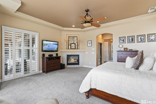 5330 Ventana Pkwy, Reno, NV 89511 - carpeted bedroom with arched walkways, baseboards, a tray ceiling, a tile fireplace, and a ceiling fan