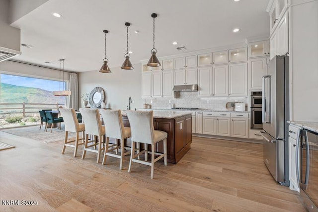 9220 Wild Skies Ct, Reno, NV 89523 - kitchen with appliances with stainless steel finishes, under cabinet range hood, a center island, white cabinetry, and tasteful backsplash