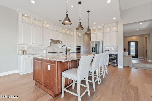 9220 Wild Skies Ct, Reno, NV 89523 - kitchen with appliances with stainless steel finishes, beverage cooler, under cabinet range hood, backsplash, and a spacious island