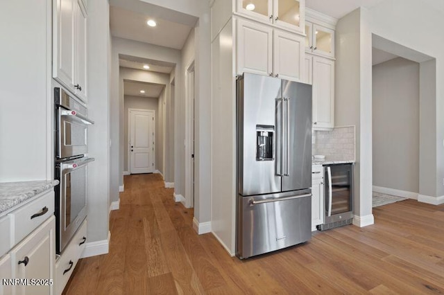 9220 Wild Skies Ct, Reno, NV 89523 - kitchen with stainless steel appliances, wine cooler, light wood-type flooring, baseboards, and white cabinets