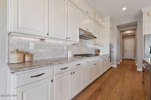9220 Wild Skies Ct, Reno, NV 89523 - kitchen with stainless steel appliances, under cabinet range hood, white cabinets, tasteful backsplash, and light wood-type flooring