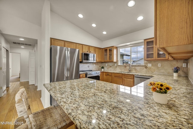 1458 Rosy Finch Dr, Sparks, NV 89441 - kitchen featuring stainless steel appliances, light stone countertops, light wood-type flooring, brown cabinets, and a sink