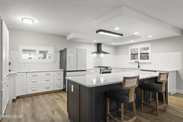 14690 Rancheros Dr, Reno, NV 89521 - kitchen featuring wall chimney range hood, gas stove, freestanding refrigerator, tasteful backsplash, and light countertops